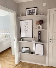 there are pictures on the wall above the shelves in this bedroom, and two framed photographs hang on the wall next to each other