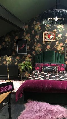 a bed room with a neatly made bed next to a purple rug and flowers on the wall