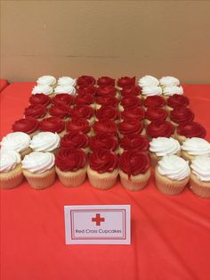 a table topped with cupcakes covered in red and white frosting