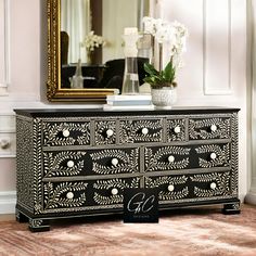 a black and white dresser with flowers on top