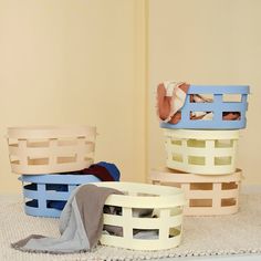 three baskets stacked on top of each other in front of a wall with clothes inside