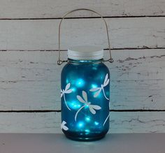 a blue glass jar with dragonflies painted on it