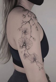 a woman's arm with flowers on it and a black mask covering her face