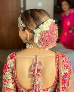 the back of a woman's dress with flowers on it and pearls in her hair