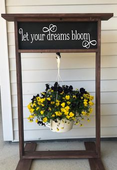 a sign that says let your dreams bloom with flowers hanging from it's side