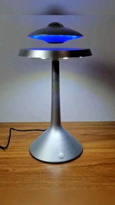 a table lamp that is on top of a wooden table with a blue light coming from it