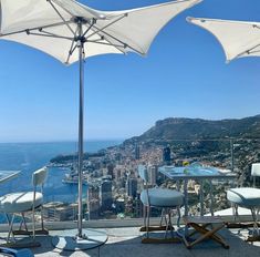 an outdoor dining area with umbrellas and chairs overlooking the cityscape in monaco