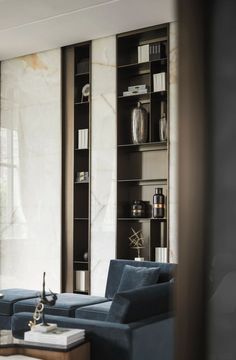 a living room with blue couches and bookshelves next to a large window