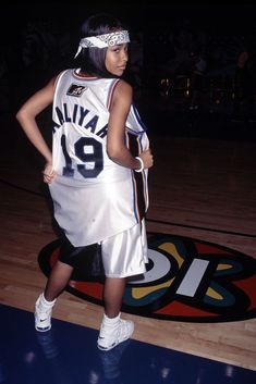 a woman in a basketball uniform standing on a court