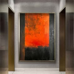 an orange and black painting hanging on the wall in a room with tile flooring