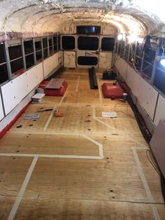 the inside of a bus with wood flooring and windows on both sides is being worked on