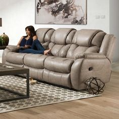 a woman sitting on top of a couch in a living room next to a coffee table