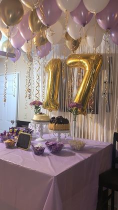 a table topped with balloons and cake next to a number seventy sign on a wall