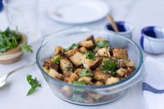 a glass bowl filled with food sitting on top of a table next to silverware