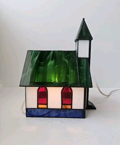 a small stained glass house with a green roof and red windows on the front side