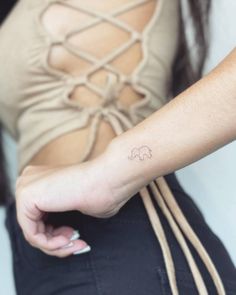 a woman's arm with a small elephant tattoo on the left side of her wrist