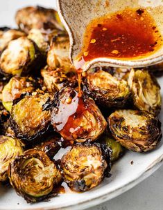 someone is pouring sauce on roasted brussel sprouts