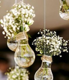 three hanging vases filled with white flowers and greenery are suspended from the ceiling