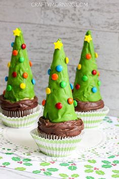 three cupcakes with green frosting and decorated christmas trees on top are sitting on a plate