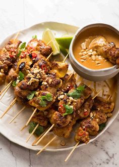 chicken skewers with peanut sauce and garnish on a white platter