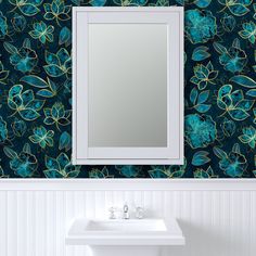 a bathroom sink sitting under a mirror next to a wall mounted faucet with flowers on it