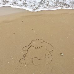 a teddy bear drawn in the sand at the beach