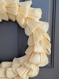 a wreath made out of corn husks hanging on the front door, ready to be decorated