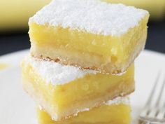 three pieces of lemon bars are stacked on top of each other with powdered sugar