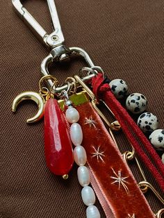 a keychain with beads and charms attached to it on a brown cloth background