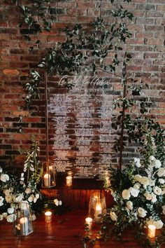 a table with candles and flowers in front of a brick wall