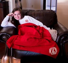 a woman sitting on a couch under a red blanket