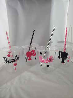 three plastic cups with straws in the shape of barbie's hair and logos on them