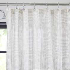 a white curtain hanging on a rod in front of a window with curtains pulled back