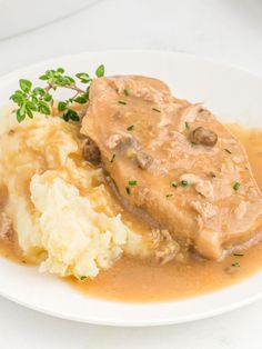 a white plate topped with mashed potatoes and gravy covered in gravy