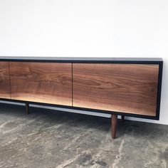 a large wooden cabinet sitting on top of a cement floor next to a white wall