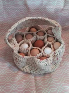 a crocheted basket filled with eggs sitting on top of a tablecloth covered surface