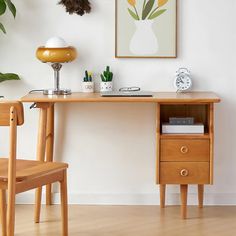 a wooden desk with two chairs and a clock on it in front of a white wall