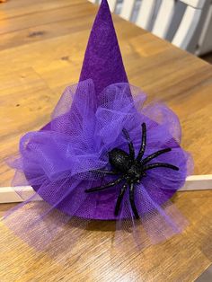 a purple witch hat sitting on top of a wooden table next to a black spider