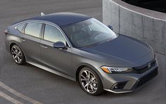 the new honda accord sedan is parked in front of a concrete wall and cement pillars