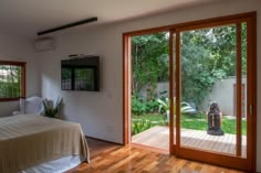 a bedroom with wooden floors and sliding glass doors leading to a backyard area that has a tv on the wall