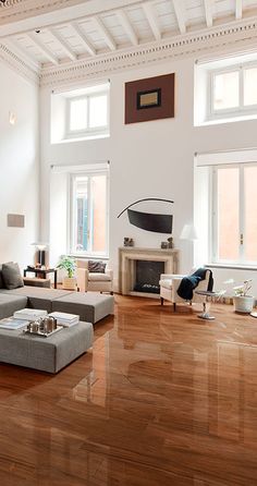 a living room filled with lots of furniture and large windows on the side of it