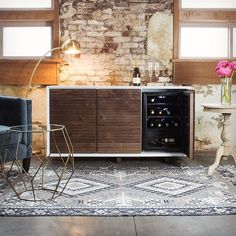 a living room with a wine cooler and two chairs in front of a brick wall