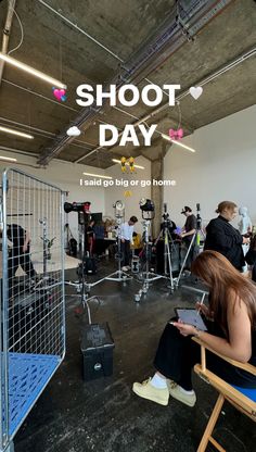 a woman sitting in a chair looking at her cell phone with the words shoot day on it