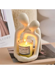 a candle that is sitting on top of a table next to a book and some pictures