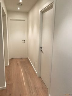 an empty hallway with white walls and wooden floors