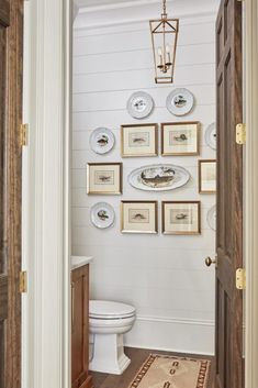 a white toilet sitting in a bathroom next to a wall filled with framed pictures on it