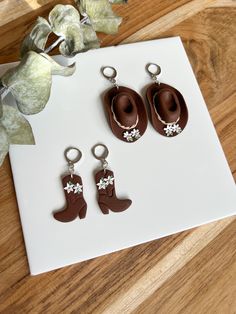 three pairs of brown cowboy boots with white flowers on them are sitting on a table