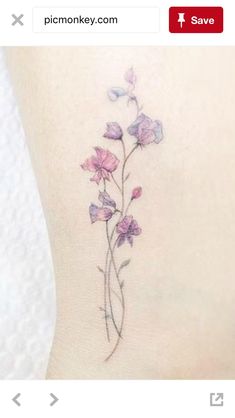 a small flower tattoo on the side of a woman's leg, with purple flowers growing out of it