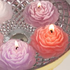 five candles with pink and purple flowers floating in water