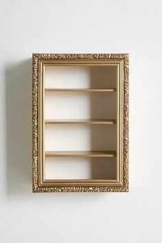 an empty gold framed shelf on the wall